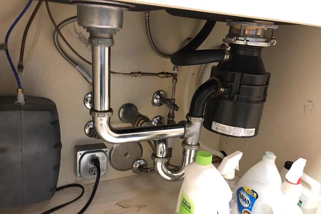Professional under-sink plumbing installation featuring a garbage disposal, P-trap assembly, and clean water lines.