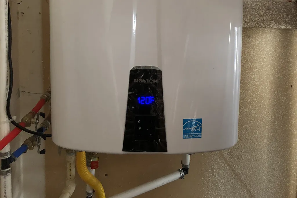 A wall-mounted Navien tankless water heater with an Energy Star seal, displaying a digital temperature of 120°F.