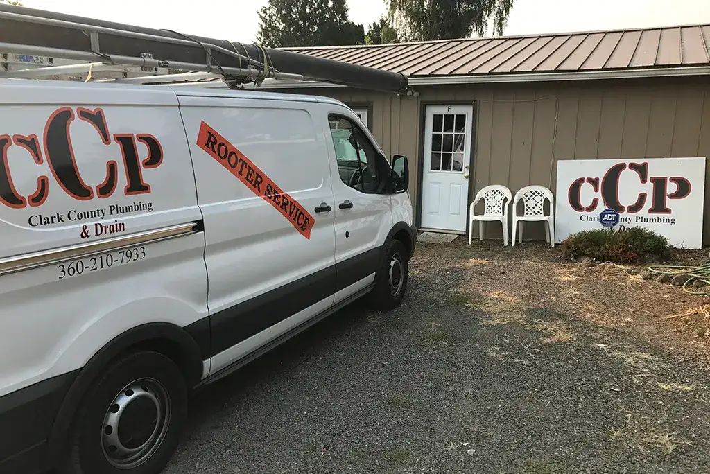 A Clark County Plumbing & Drain service van with "Rooter Service" branding parked in front of the company office.