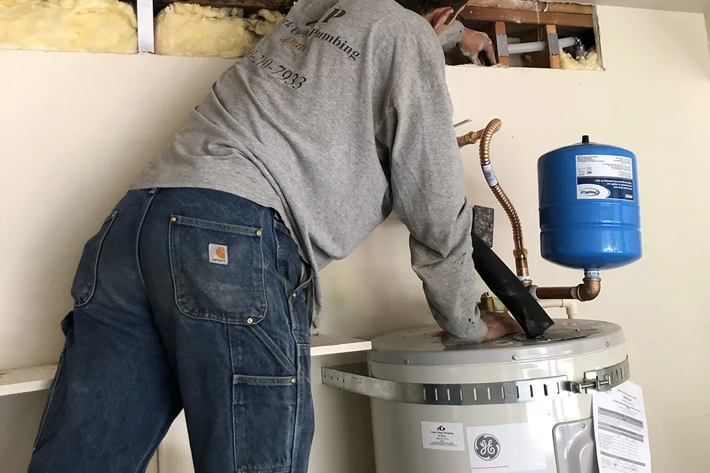 A Clark County Plumbing technician installing a GE water heater with an expansion tank and new PEX piping connections.