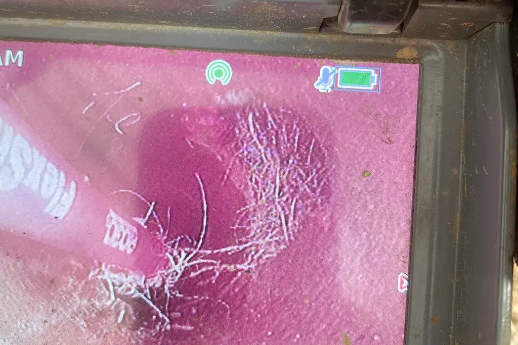 Close-up of a plumbing diagnostic monitor displaying a significant root intrusion blockage inside a residential sewer line.