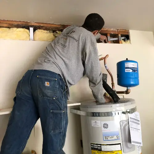 A Clark County Plumbing technician installing a GE water heater with an expansion tank and new PEX piping connections