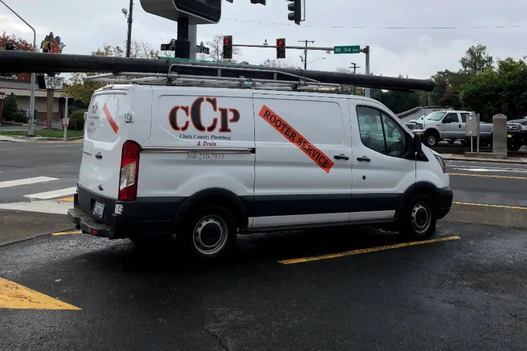 A Clark County Plumbing & Drain service van with "Rooter Service" branding parked near a commercial intersection